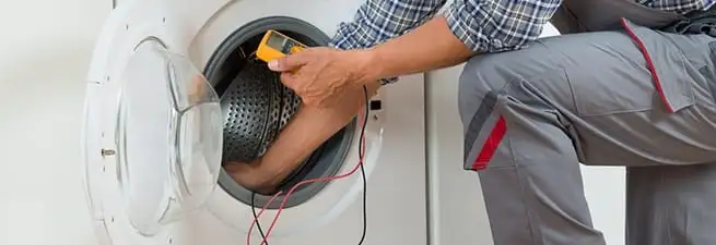 Dryer repair technician inspecting and repairing a clothes dryer in Jackson, MS