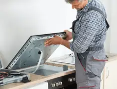 Appliance repair technician installing a built-in cooktop in Jackson, MS