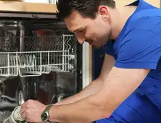 Dishwasher repair technician inspecting and servicing an open dishwasher in Jackson, MS