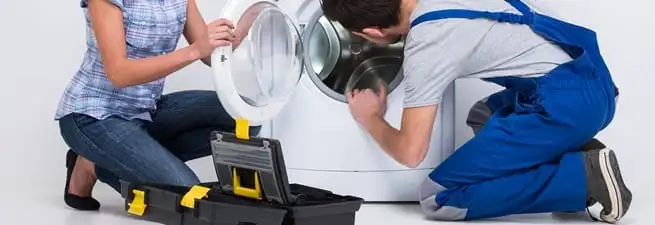 Washer repair technician inspecting a front-load washing machine with tools in Jackson, MS