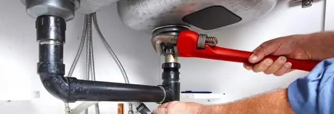 Garbage disposal repair technician tightening the sink drain and disposal connection in Jackson, MS