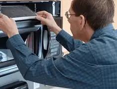 Appliance repair technician replacing a microwave vent filter in Jackson, MS