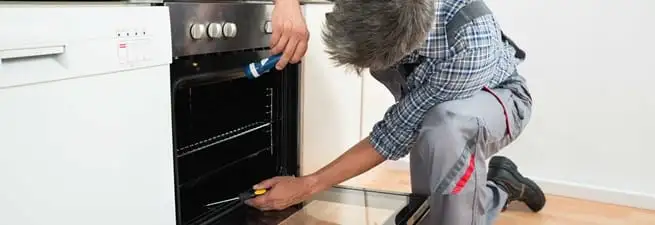 Oven repair technician inspecting and servicing an electric oven in Jackson, MS