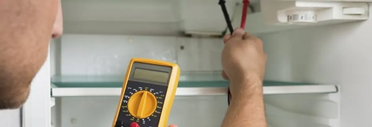 Refrigerator repair technician testing electrical components with a multimeter in Jackson, MS