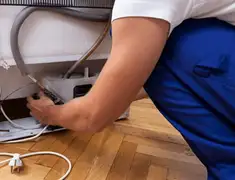 Appliance repair technician fixing refrigerator water line and connections in Jackson, MS