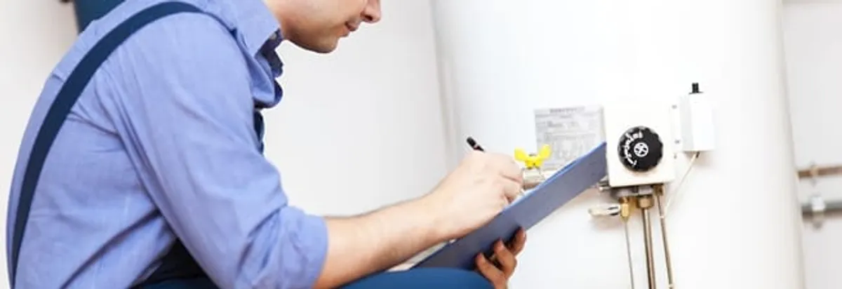 Water heater repair technician inspecting the unit and recording service notes in Jackson, MS
