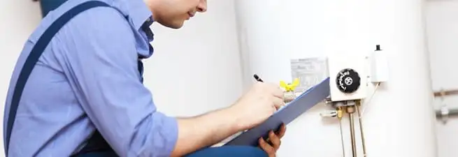 Water heater repair technician inspecting the unit and recording service notes in Jackson, MS
